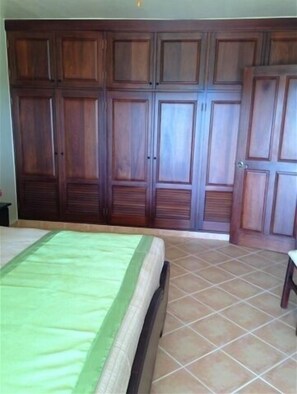 A bedroom with a large wardrobe, a bed with a green bedspread, and tiled flooring. - Casa Lilly B&B Cabarete (Cabarete)