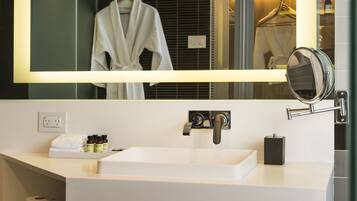 A modern bathroom with a large mirror, a white sink, and a towel rack.