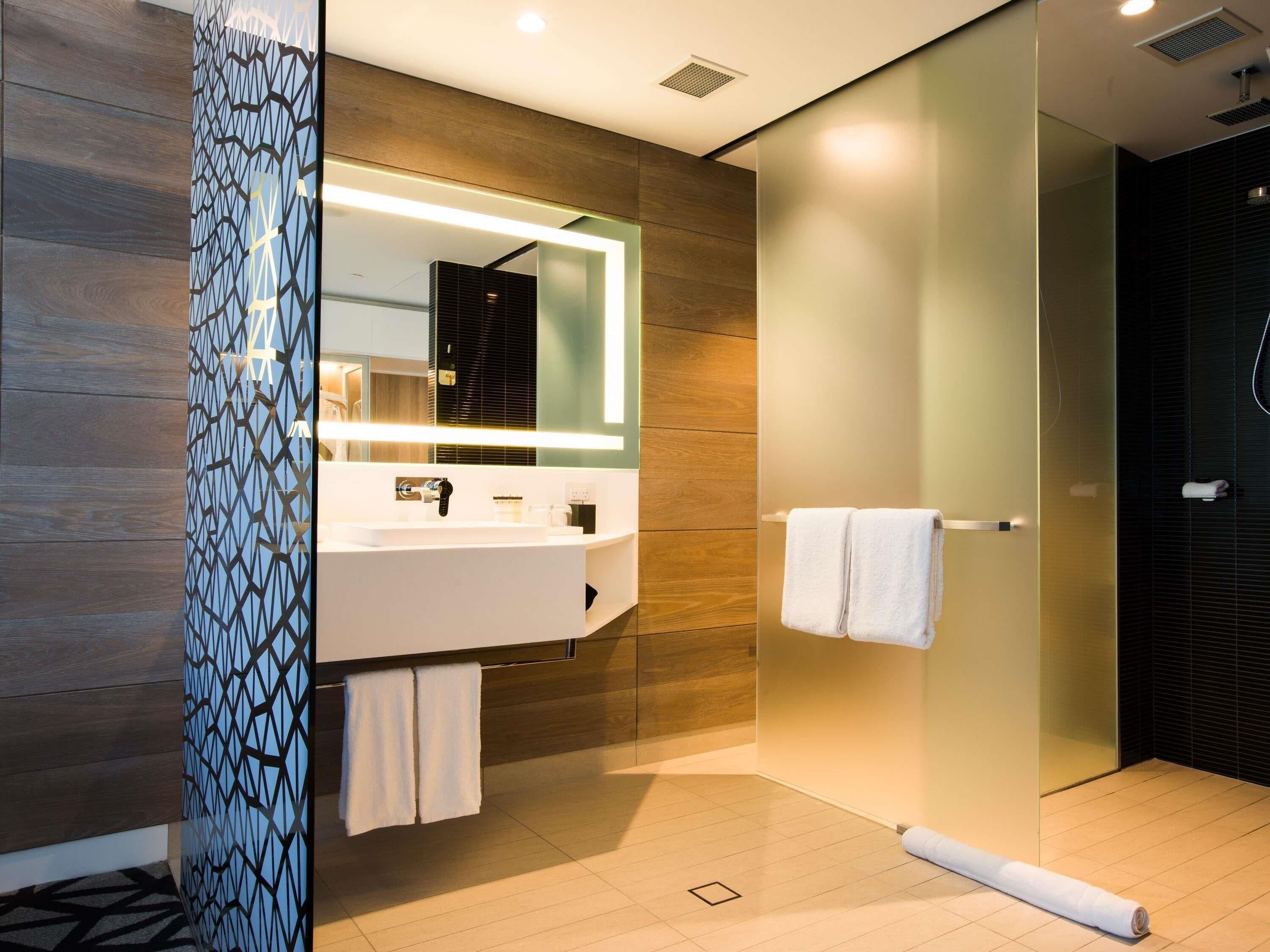 Un baño moderno con un espejo grande, un lavabo blanco y una zona de ducha.