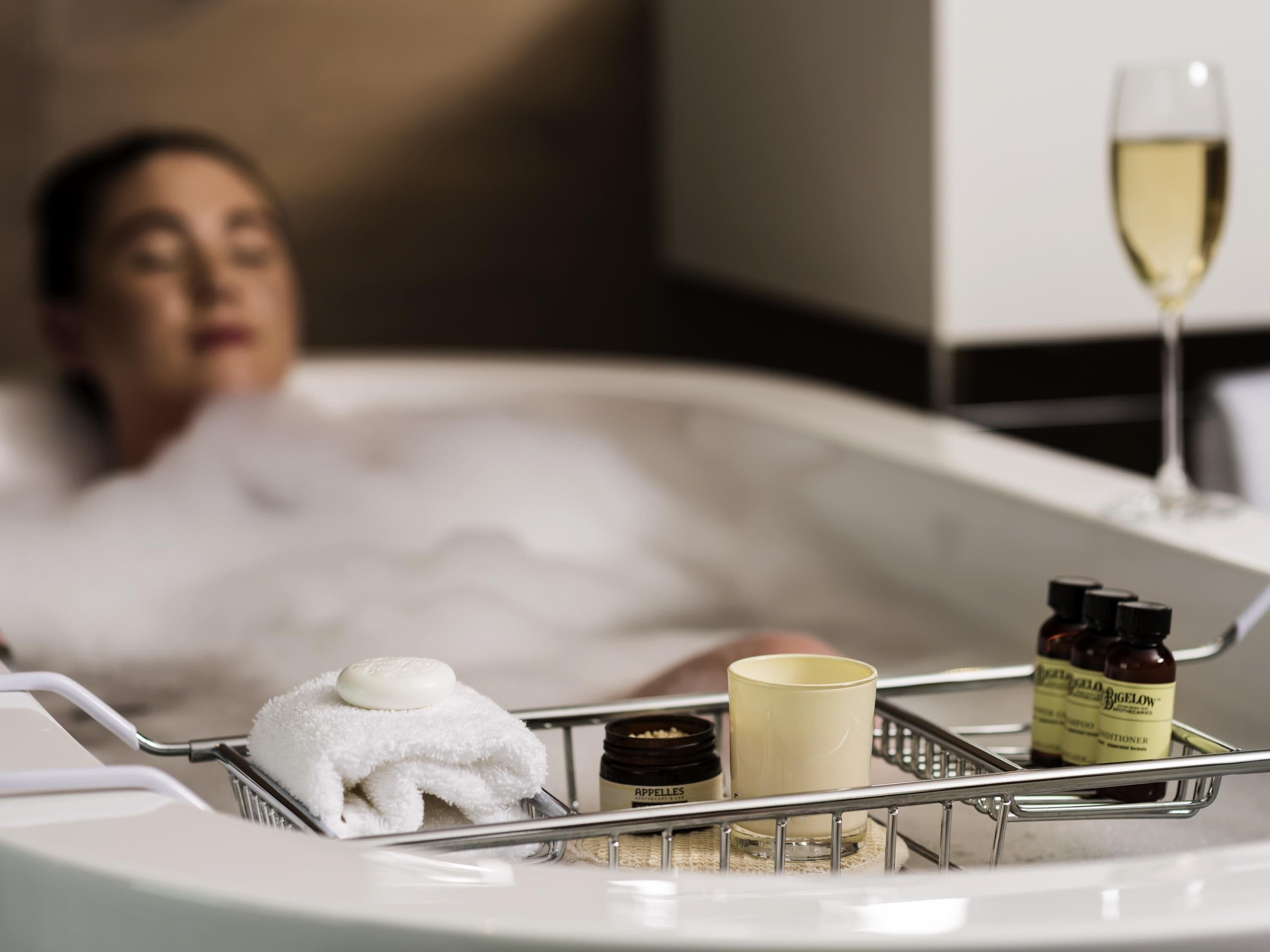 A spa bath with a towel, candles, and bath products.