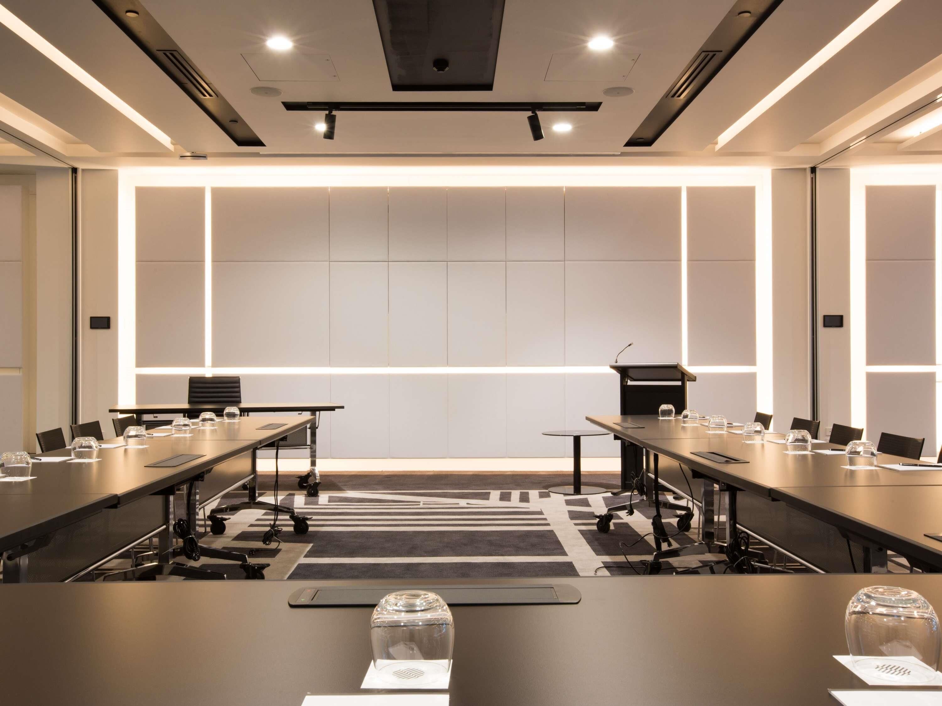 A conference room with a long table, chairs, a podium, and a large window.