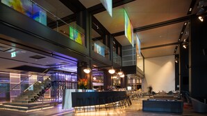 A modern bar area with a counter, stools, and a staircase leading to an upper level. - Pullman Sydney Airport (Mascot)
