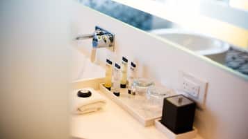 A bathroom vanity with a white countertop, a towel, and a set of toiletries including a black box, a glass container, and several bottles.