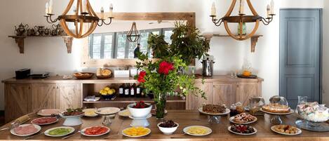 A wooden dining table set with various dishes, a vase with flowers, and two chandeliers.