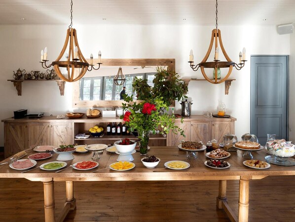 Una mesa de comedor de madera dispuesta con diversos platos, un florero con flores y dos candelabros.