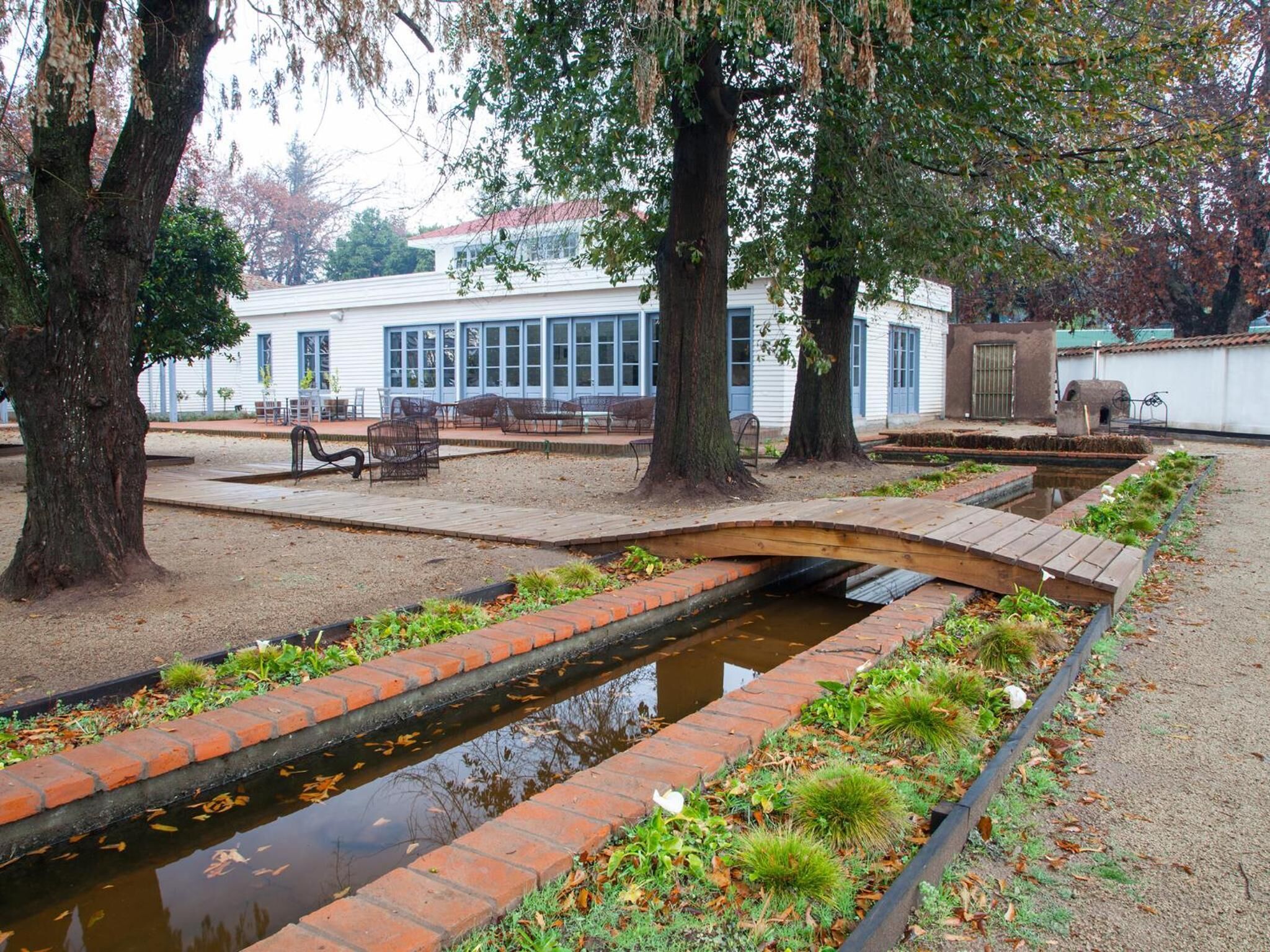 Un patio tranquilo con una pequeña fuente, bancos y árboles.
