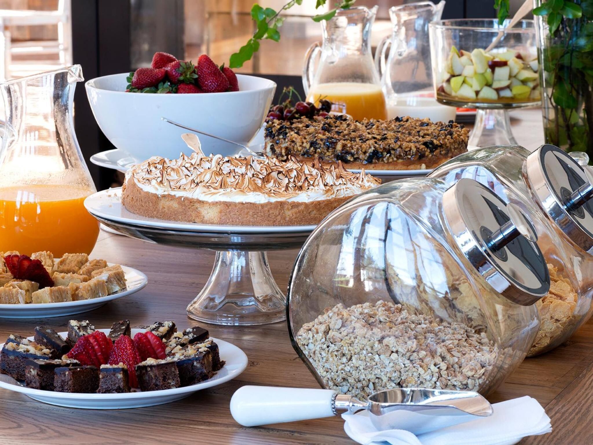 A breakfast buffet with various dishes including a cake, granola, and fruit.