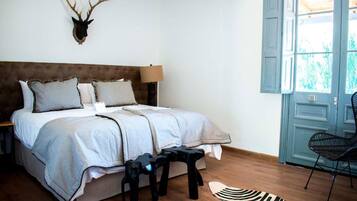 A bedroom with a bed, a mounted deer head, a zebra-patterned rug, and a chair by the window.