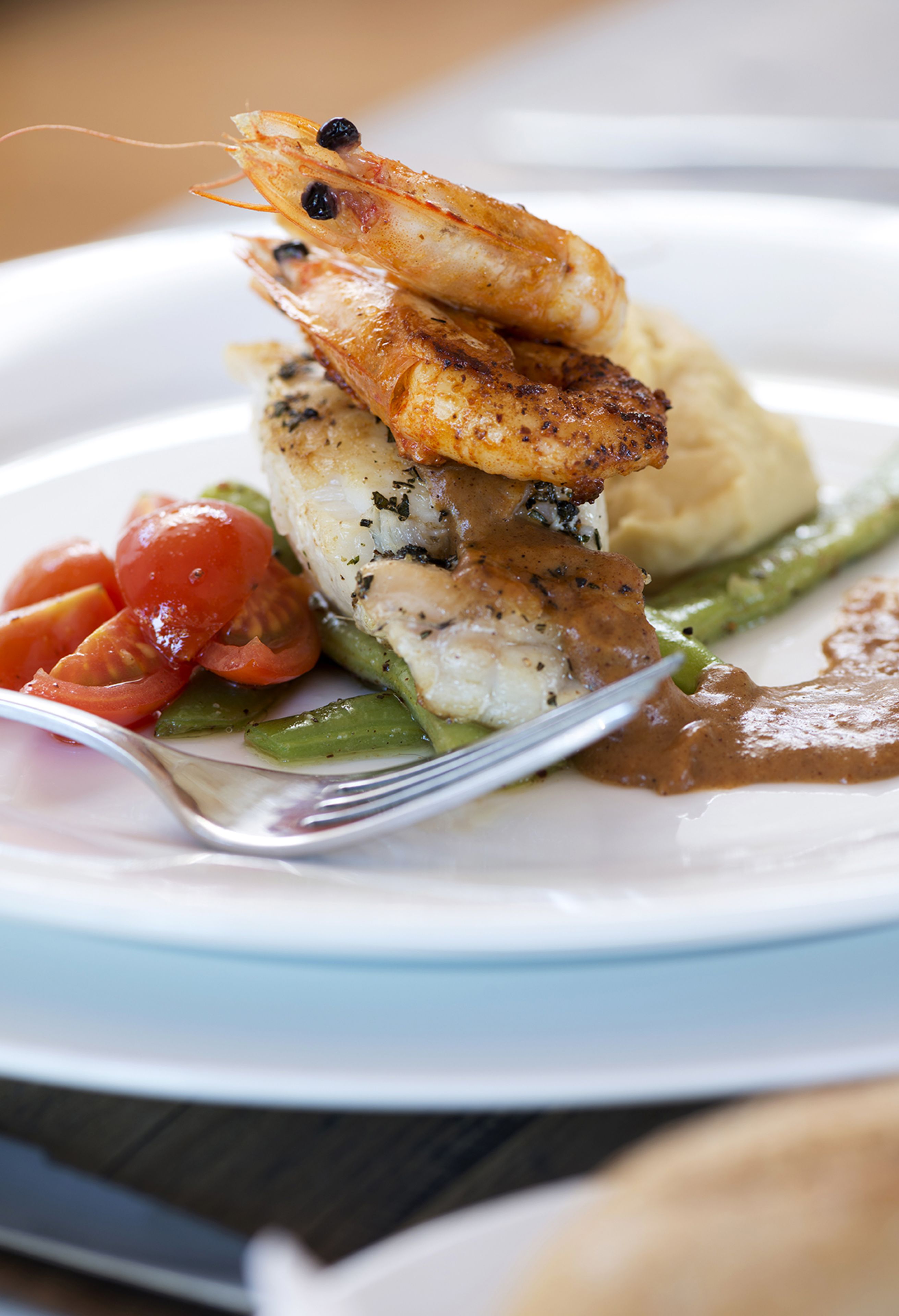 A plate of food with shrimp, fish, asparagus, and tomatoes.