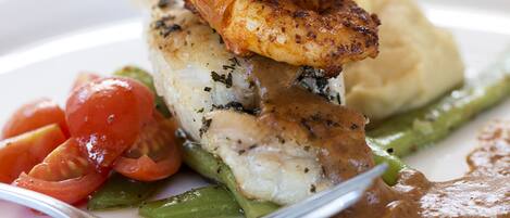 A plate of food with shrimp, fish, asparagus, and tomatoes.