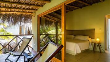 Una habitación con una cama, una mesita de noche, una silla y vistas a palmeras a través de una ventana.