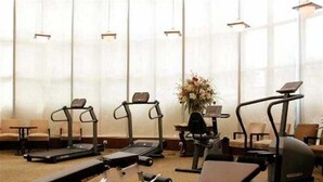 Een sportschool met loopbanden, elliptische trainers en een plek voor de bankdrukpers.