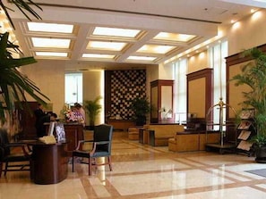 Un hall d’hôtel comprenant un comptoir d’enregistrement, un espace salon et un mur décoré de motifs.