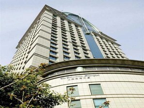 A tall building with a curved base and multiple windows. - South China Harbour View Hotel (Shanghai)