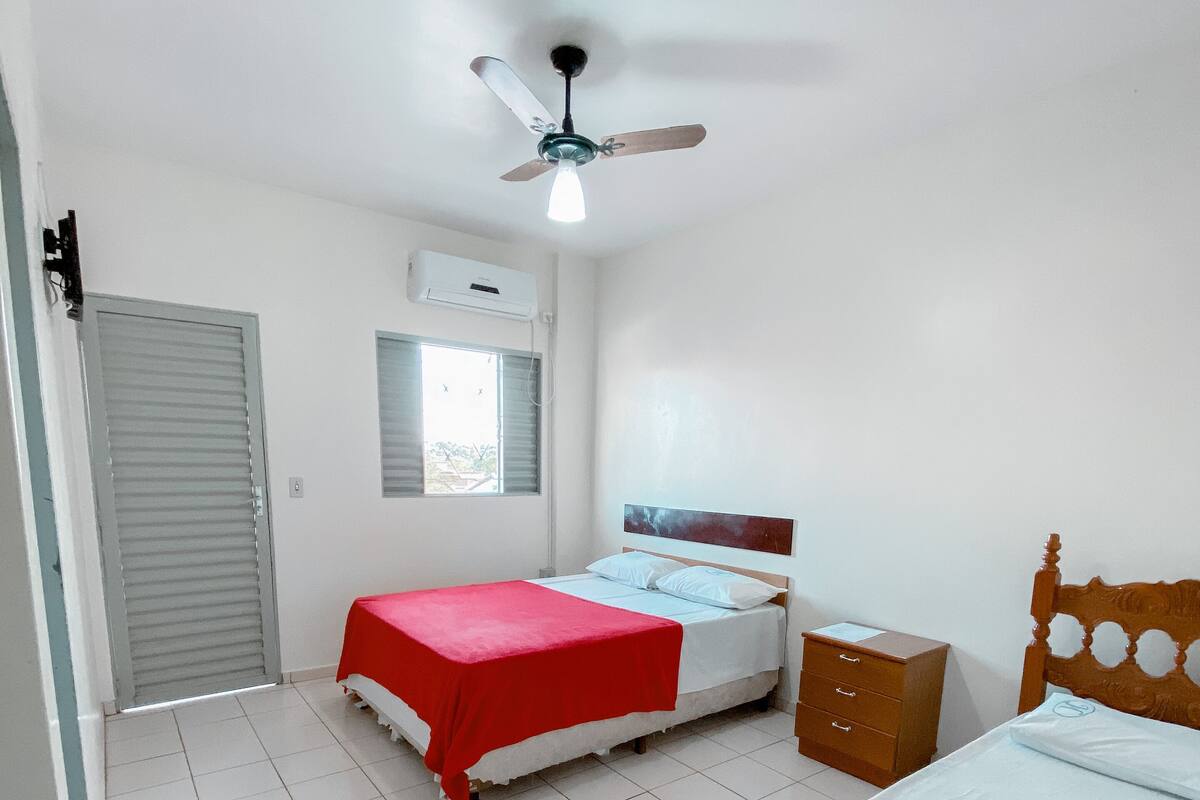 Une chambre avec deux lits, un ventilateur de plafond, un appareil de climatisation et une fenêtre.