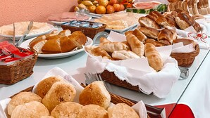 Une table de buffet proposant une variété de pains, de viennoiseries et de fruits.