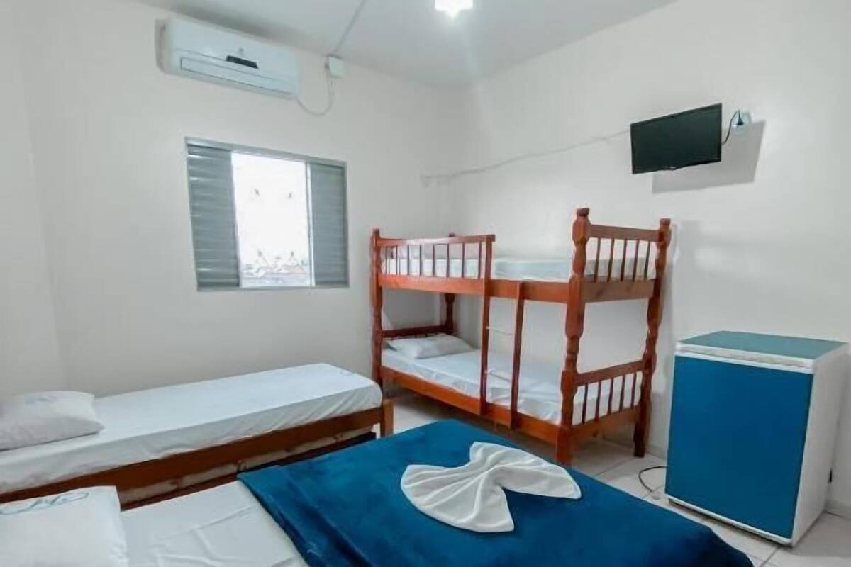 Une chambre avec des lits superposés, un ventilateur de plafond, une télévision et une fenêtre.