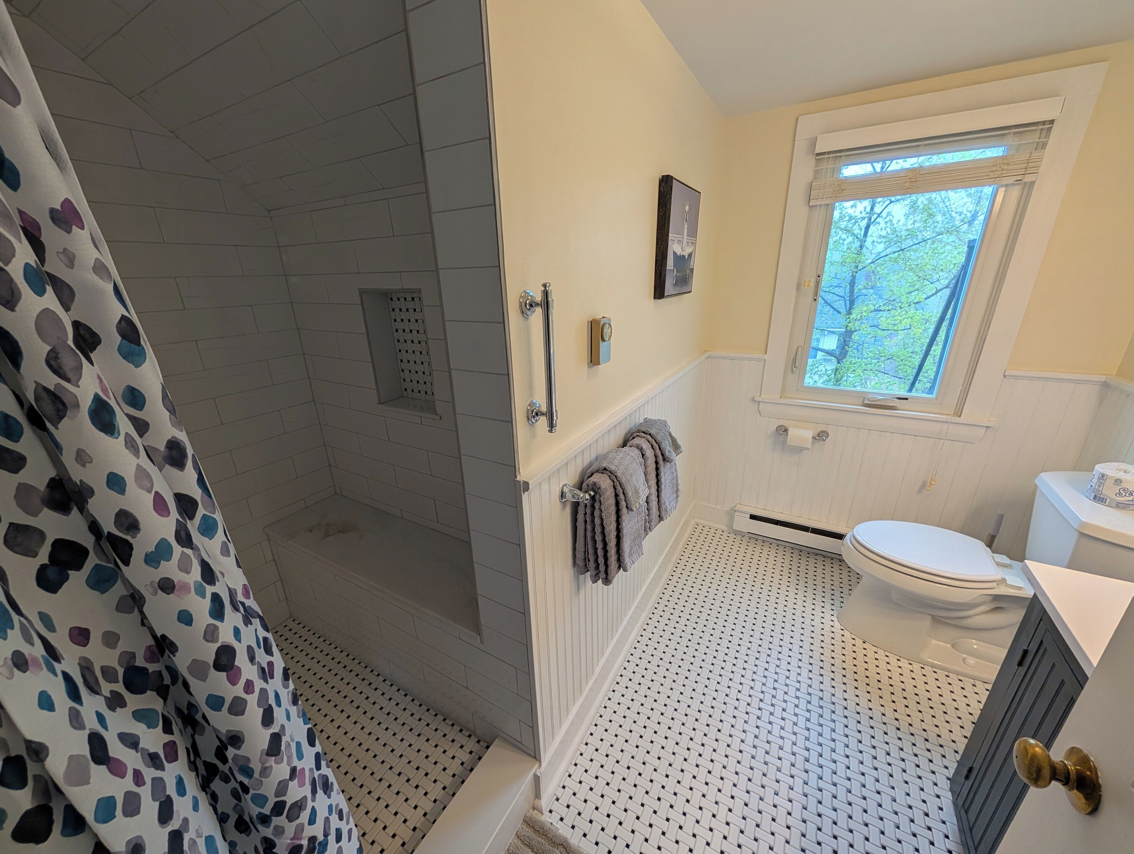 Un baño con ducha, inodoro y ventana.
