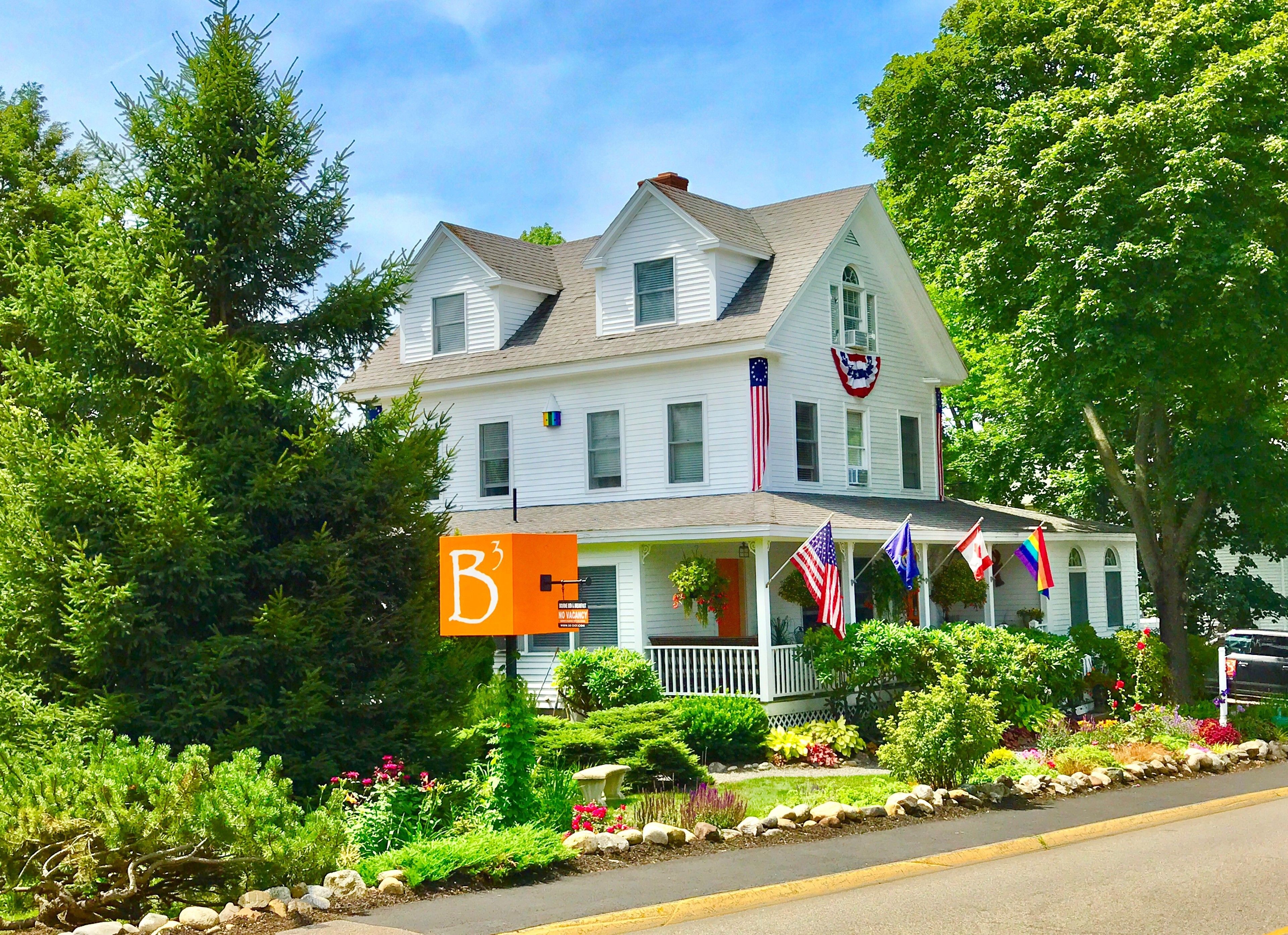 A two-story house with a porch, American flags, and a 'B3' sign.