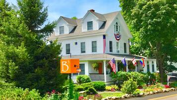 A two-story house with a porch, American flags, and a 'B3' sign.