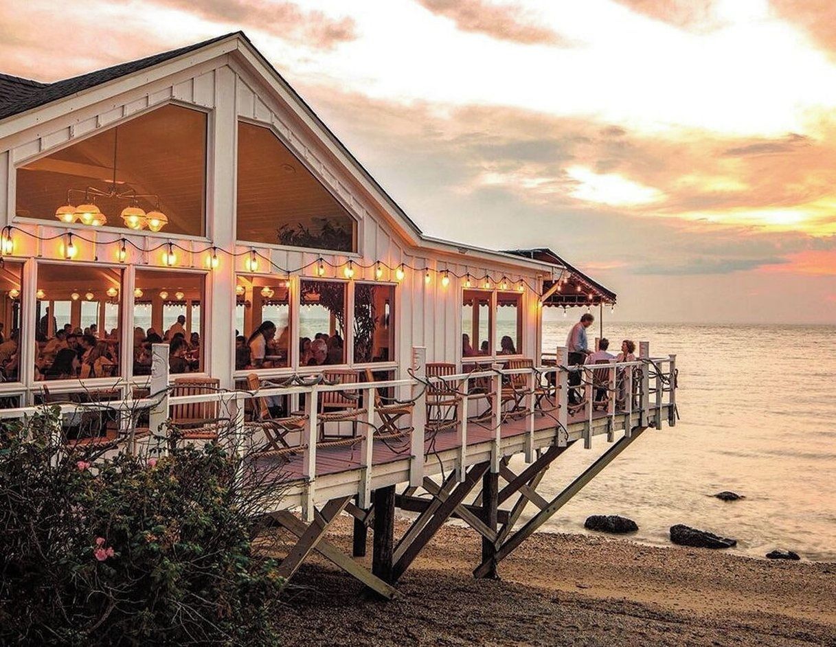 A waterfront restaurant with outdoor seating and a view of the sea.