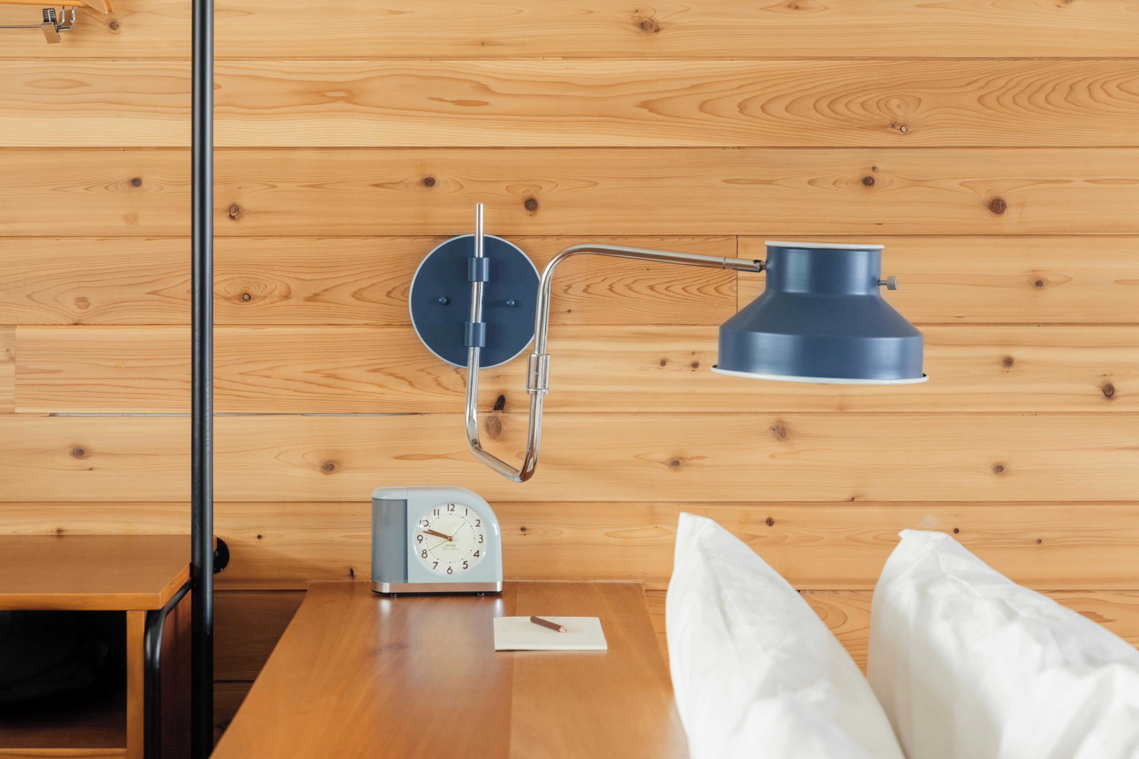 Una pared de madera con un reloj y una lámpara de escritorio.
