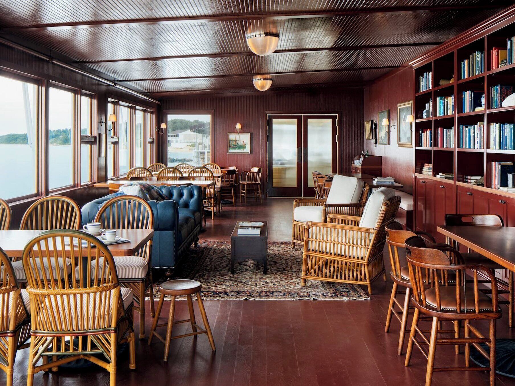 A cozy, well-lit room with wooden floors, a large bookshelf, and comfortable seating areas.