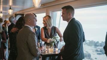 A group of people at a social event inside a building with a view of the outdoors.
