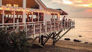 A seaside restaurant with outdoor seating, a deck, and a view of the ocean. - Sound View Greenport (Greenport)