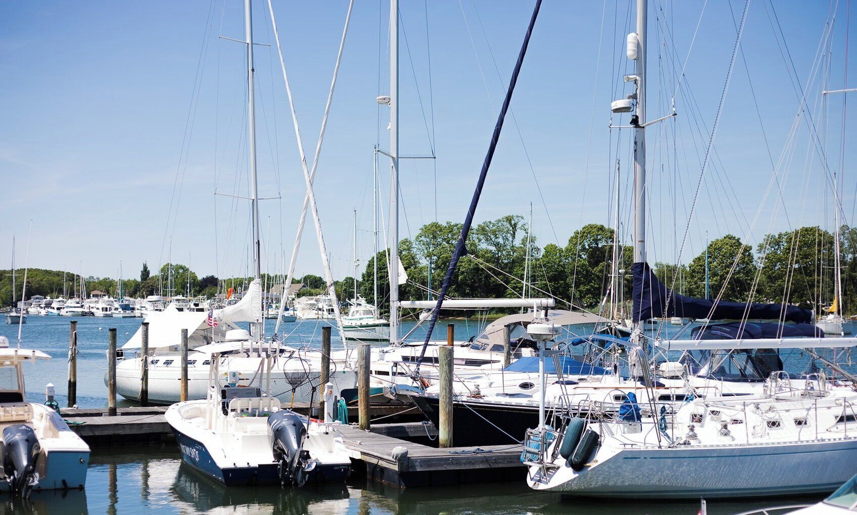 A marina with multiple boats docked at wooden piers.