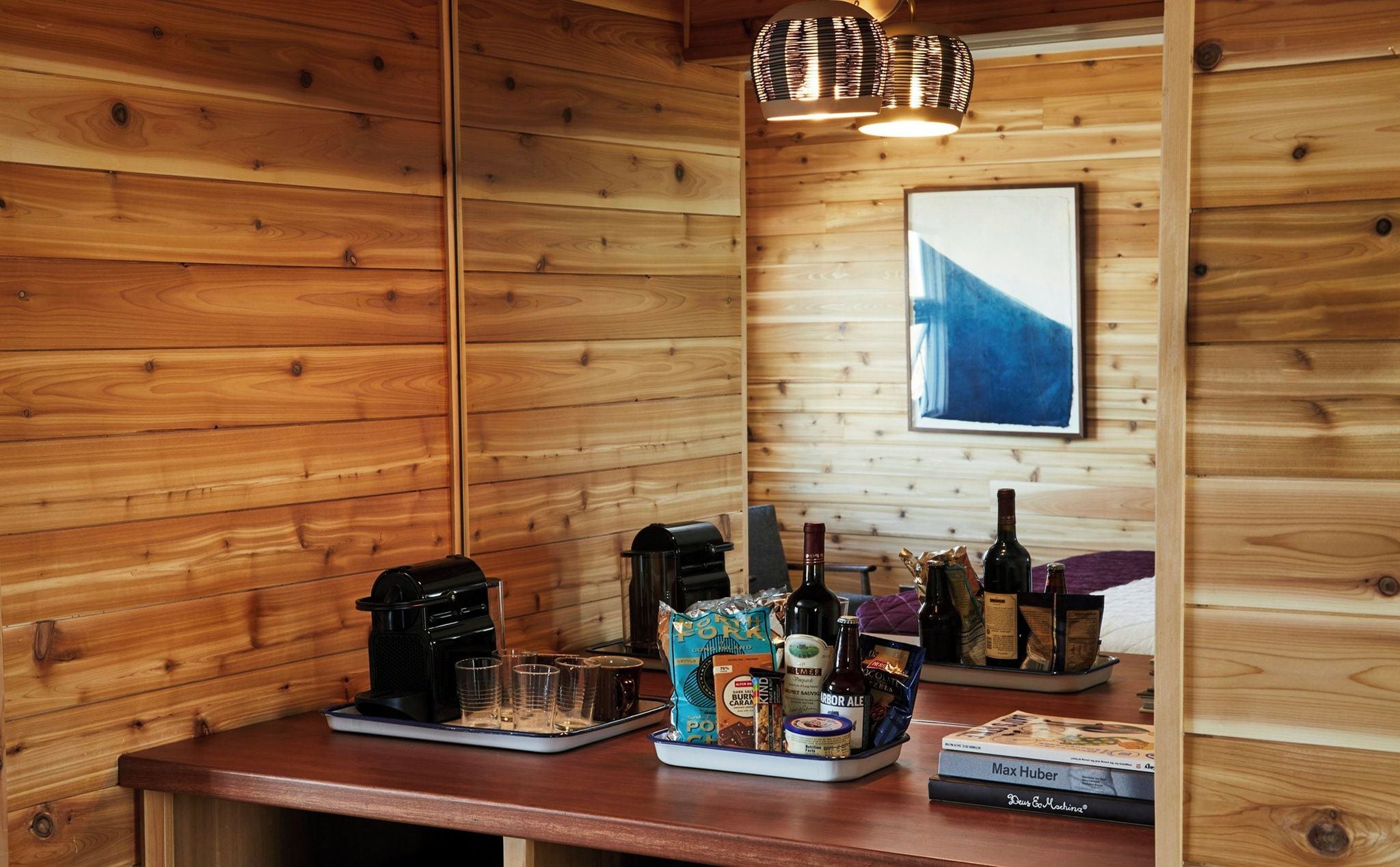Un interior de madera con una cafetera, aperitivos y bebidas sobre una encimera.