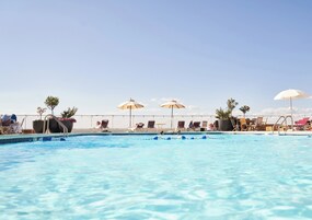 Una piscina al aire libre de temporada, sombrillas