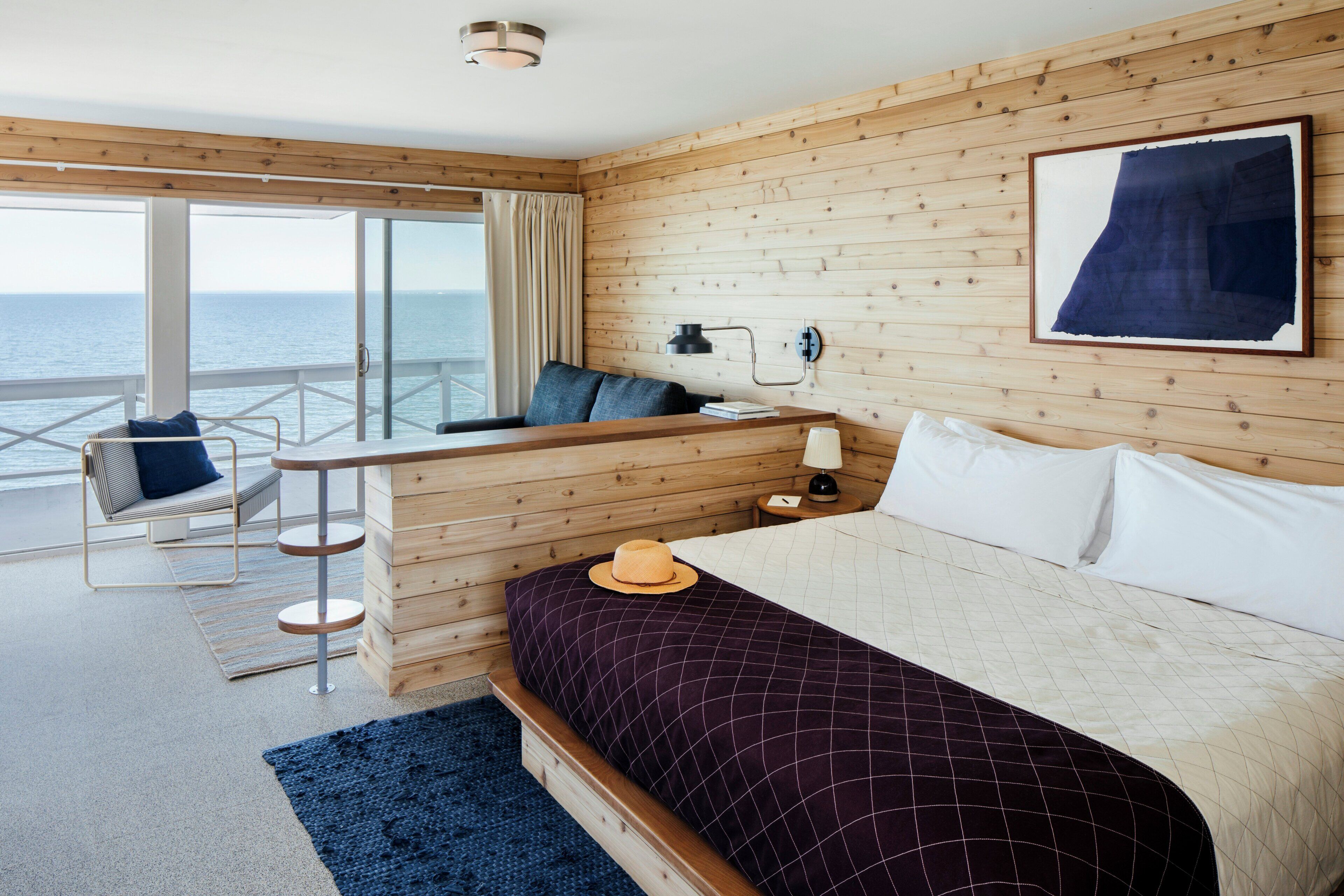 Habitación de hotel con cama, escritorio, silla y vista al mar.