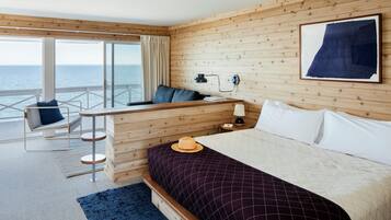 Habitación de hotel con cama, escritorio, silla y vista al mar.