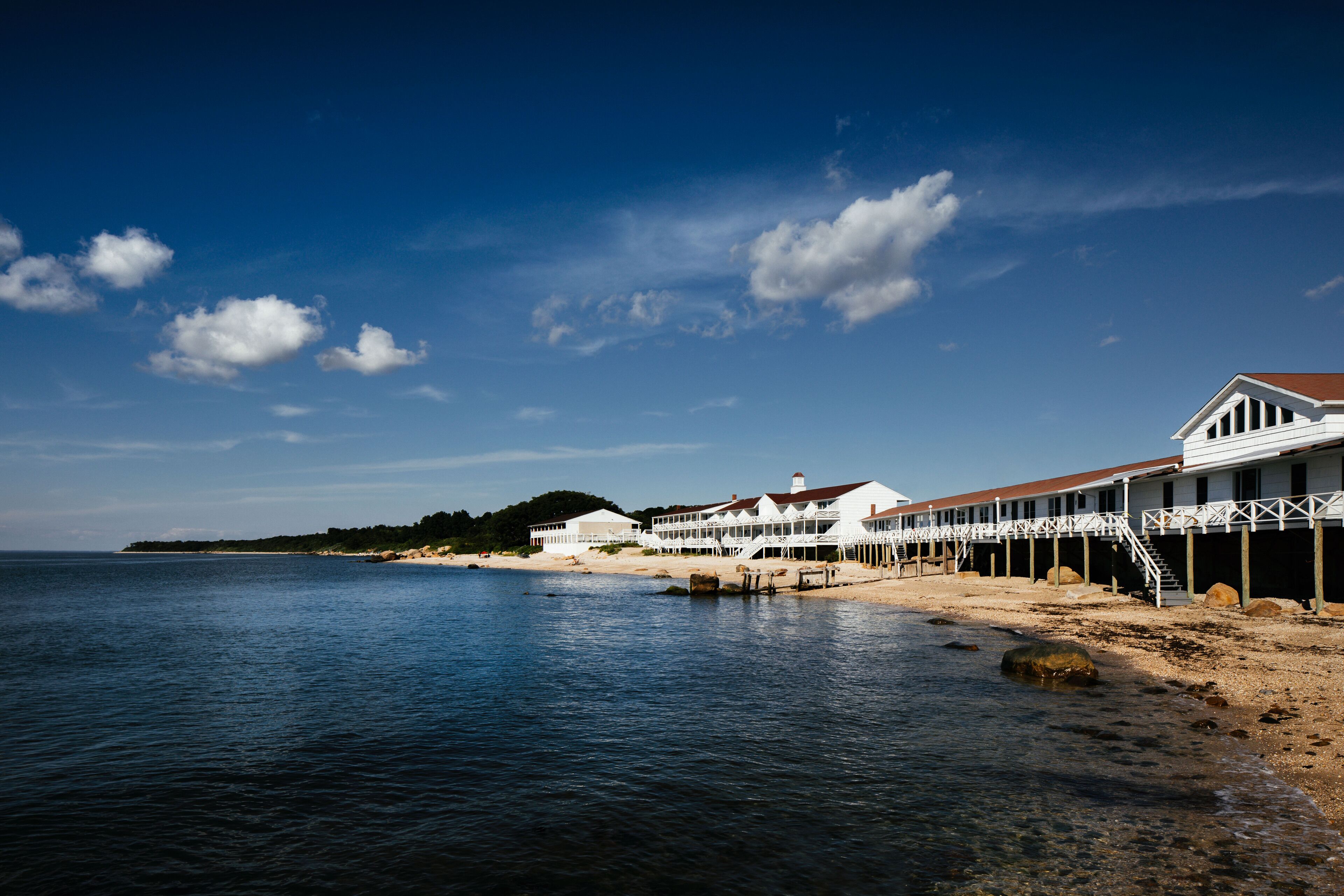 Un hotel frente al mar con vista a la playa, un muelle y una montaña al fondo.