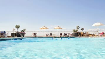 Una piscina al aire libre de temporada, sombrillas, tumbonas