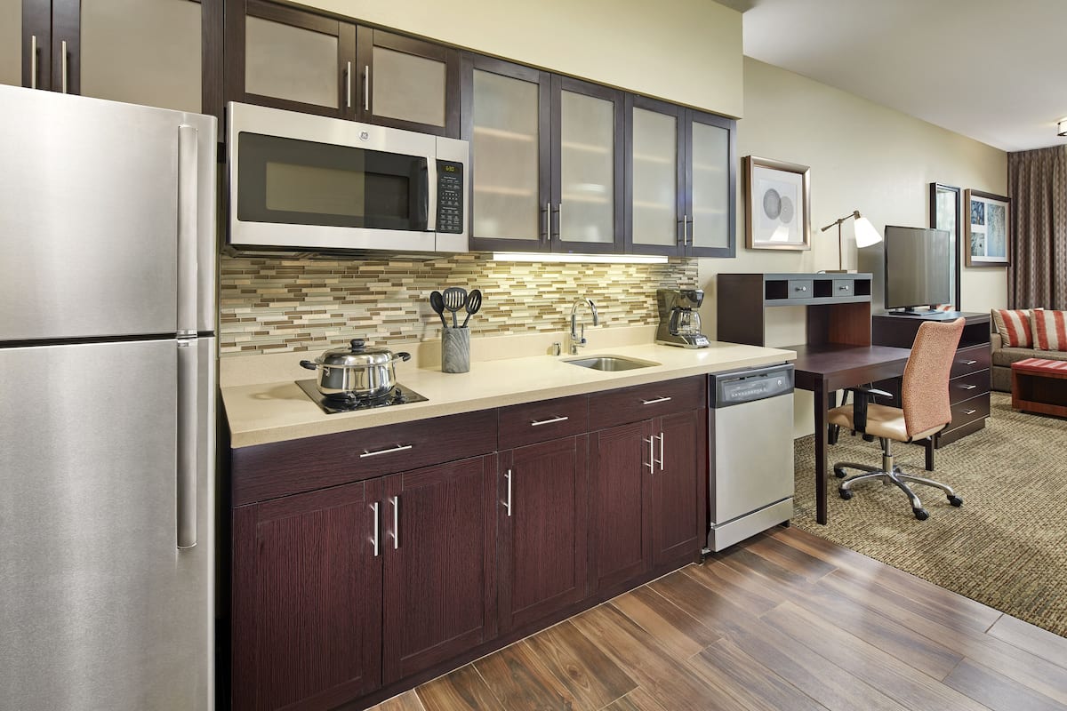 A modern kitchen with stainless steel appliances, dark wood cabinets, and a tiled backsplash.