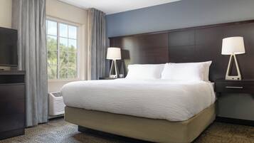 A hotel room with a large bed, two bedside lamps, a TV, and a window with curtains.