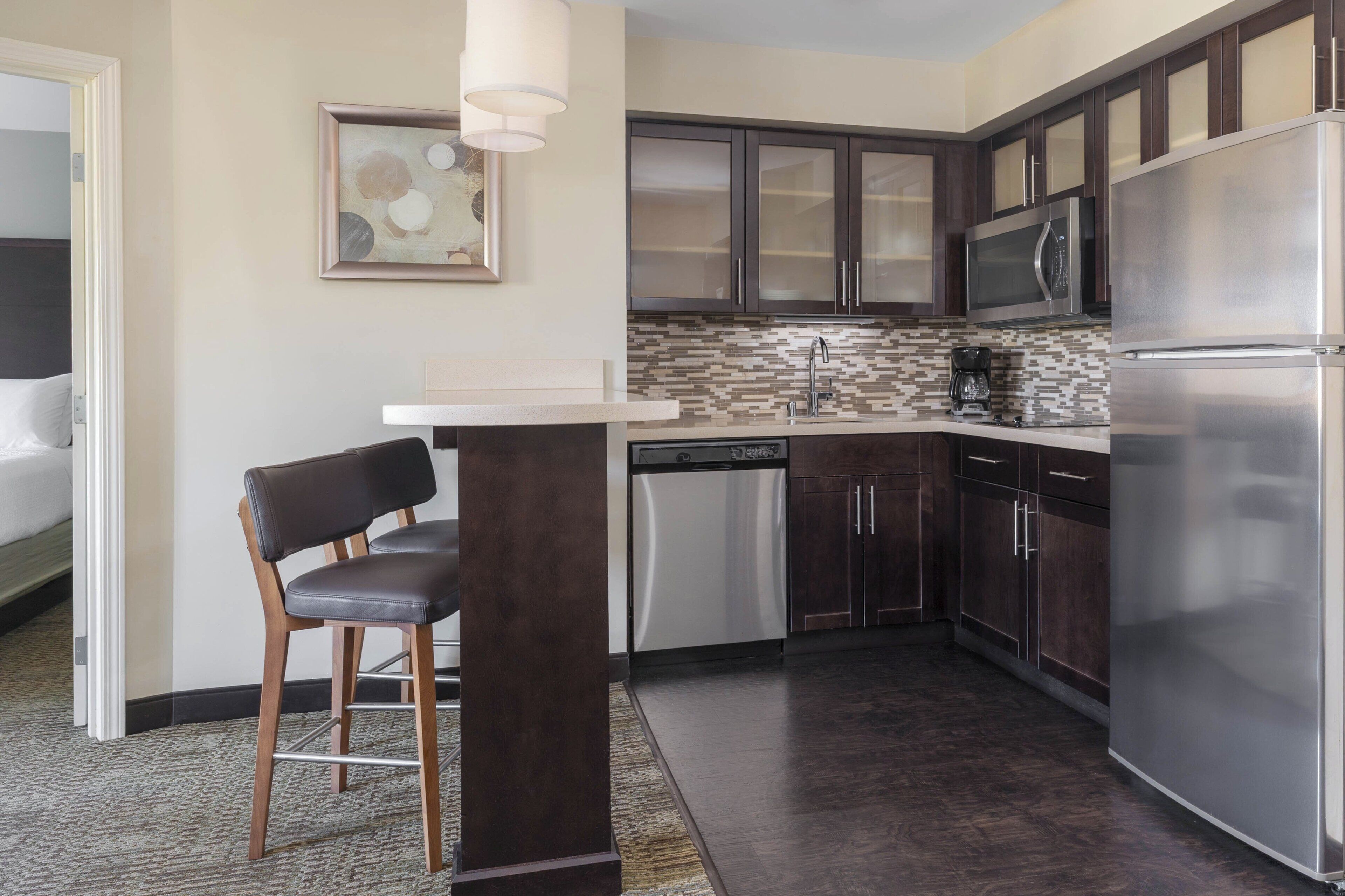 A modern kitchen with dark wood cabinets, stainless steel appliances, and a tiled backsplash.