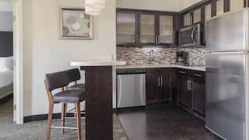 A modern kitchen with dark wood cabinets, stainless steel appliances, and a tiled backsplash.