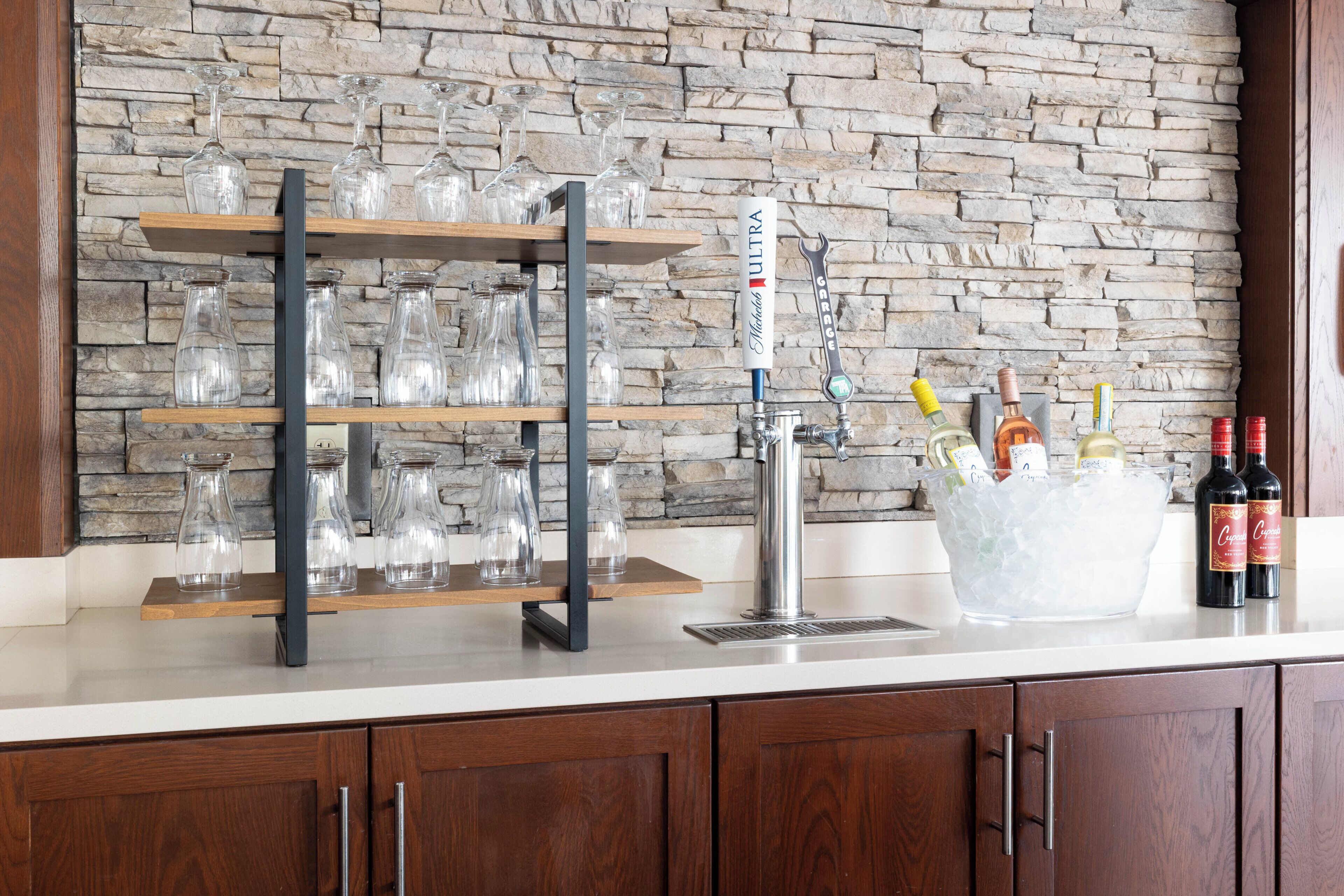 A bar area with a stone wall, a wine bottle holder, and a tap.