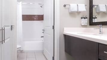 A modern bathroom with a shower, toilet, and vanity with a mirror.