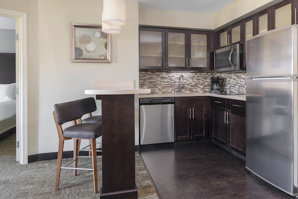 Una cocina moderna con armarios de madera oscura, electrodomésticos de acero inoxidable y un salpicadero de azulejos.
