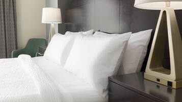 A hotel room with a bed, a nightstand, a lamp, and a green chair.