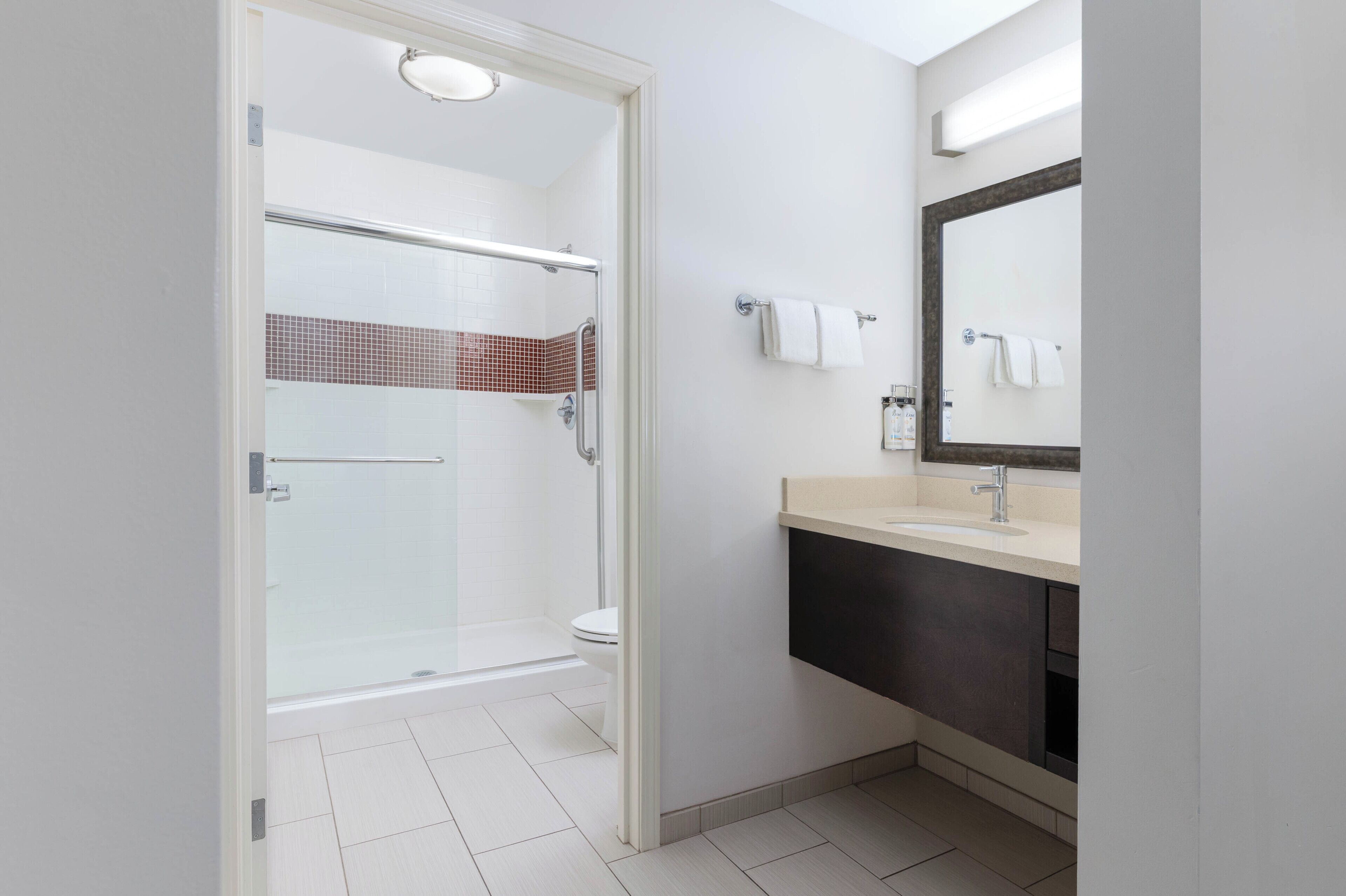 A modern bathroom with a glass shower enclosure, a toilet, a sink with a mirror, and a towel rack.