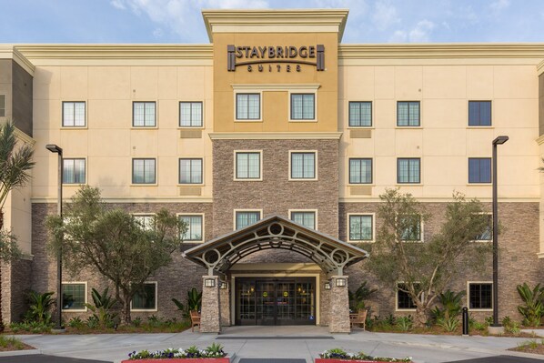 A Staybridge Suites hotel with a symmetrical facade, multiple windows, and a central entrance with a decorative arch. - Staybridge Suites Corona South by IHG (Corona)