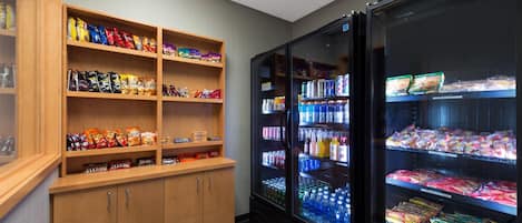 Un área de venta automática con estantes llenos de diversos aperitivos y una sección refrigerada con bebidas embotelladas.
