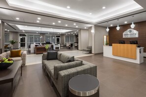 A modern hotel lobby with a reception desk, seating area, and a dining space. - Wingate by Wyndham Loveland (Loveland)