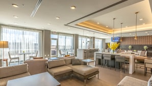 A modern hotel lobby with a seating area, a bar, and a television screen. - Wingate by Wyndham Loveland (Loveland)
