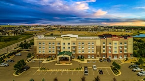 A large hotel with a central entrance, multiple parking lots, and a surrounding landscape. - Wingate by Wyndham Loveland (Loveland)